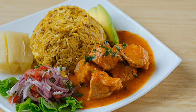 Stew of meat served with rice, lentils, salad and avocado