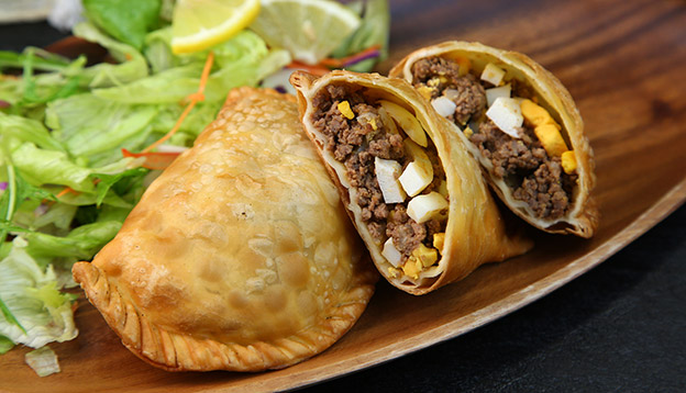 a plate of empanadas cut open to show the filling.