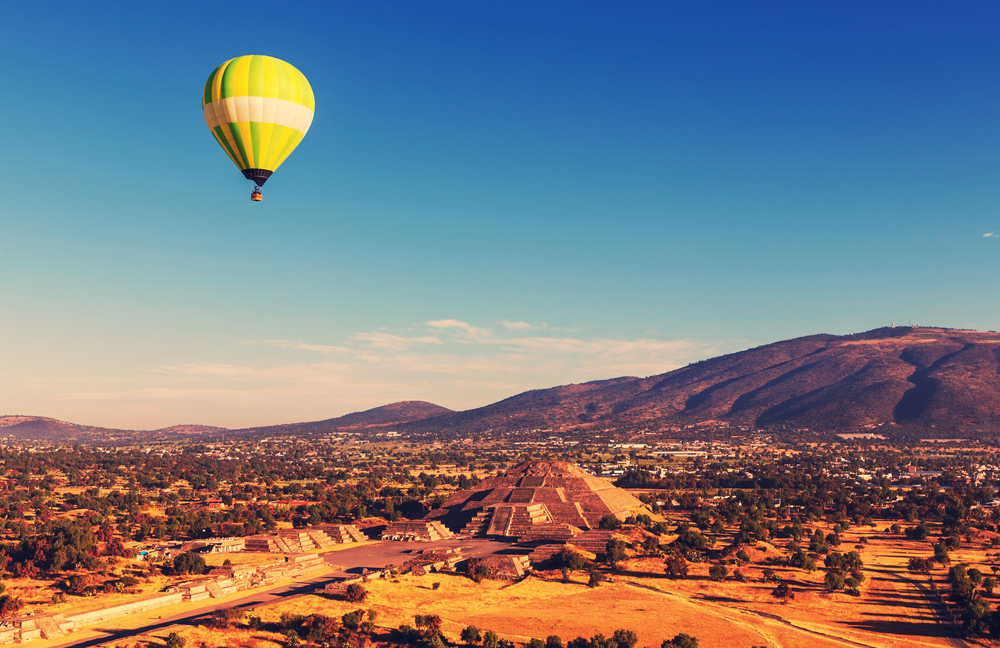 acient pyramid with hot air baloon floating in the air