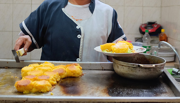 A cook preparing llapingachos - a typical dish from the central Andean region of Ecuador.