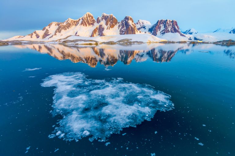 mountain range with snow next to the sea