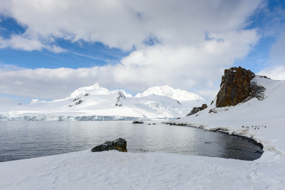 mountains covered with ice next to the sea